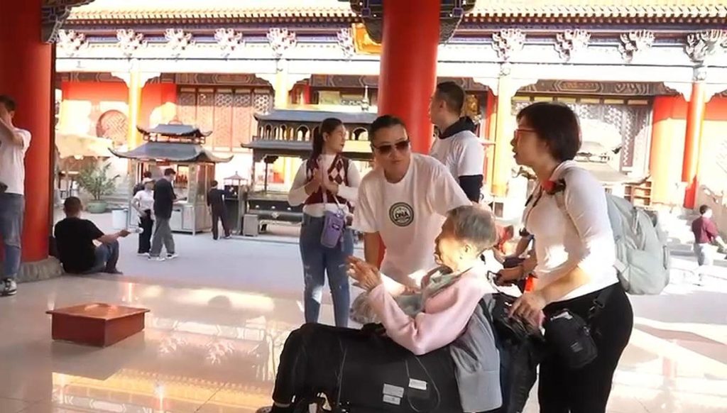 私董善愛行動中，義工陪同 84 歲婆婆坐輪椅走訪東莞舊城區，展現黃君俠倡導的溫柔陪伴與女性照顧力量