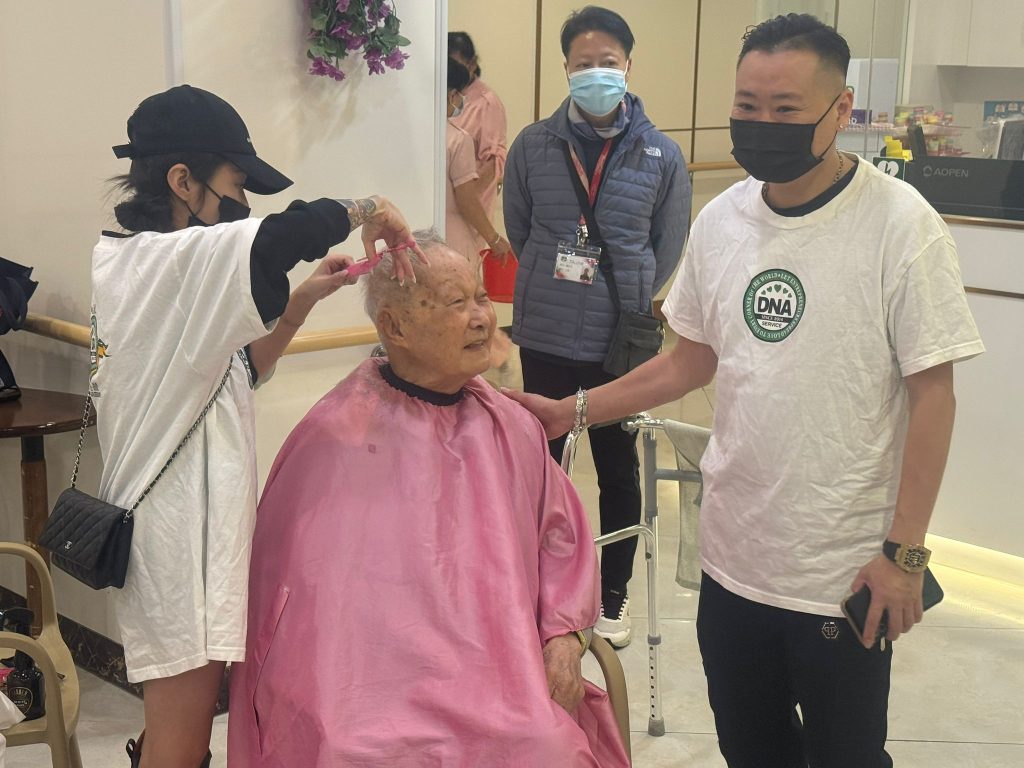 私董善愛長者義剪活動現場，義工與長者合影留念，黃君俠出席參與社區公益行動。