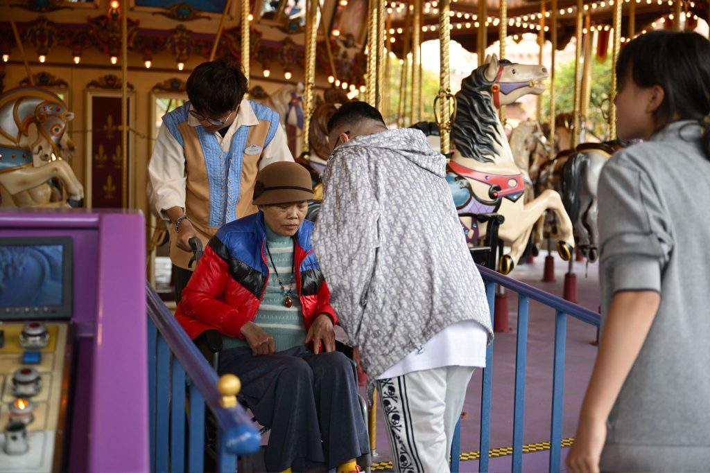 Grace嫲嫲於迪士尼與家人同行並嘗試行走，黃君俠在旁陪同，私董善愛主辦長者外出活動