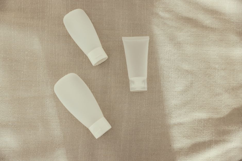 護膚產品平鋪：防曬、精華、乳霜、毛巾與植物，簡約木桌自然光