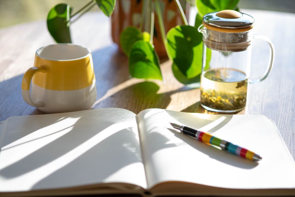 晨光下的桌面：筆記本、茶杯與小花瓶