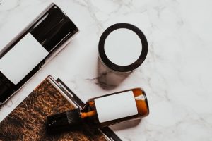護膚品平鋪圖：毛巾、精華瓶、防曬與植物在木桌晨光下的簡潔擺設